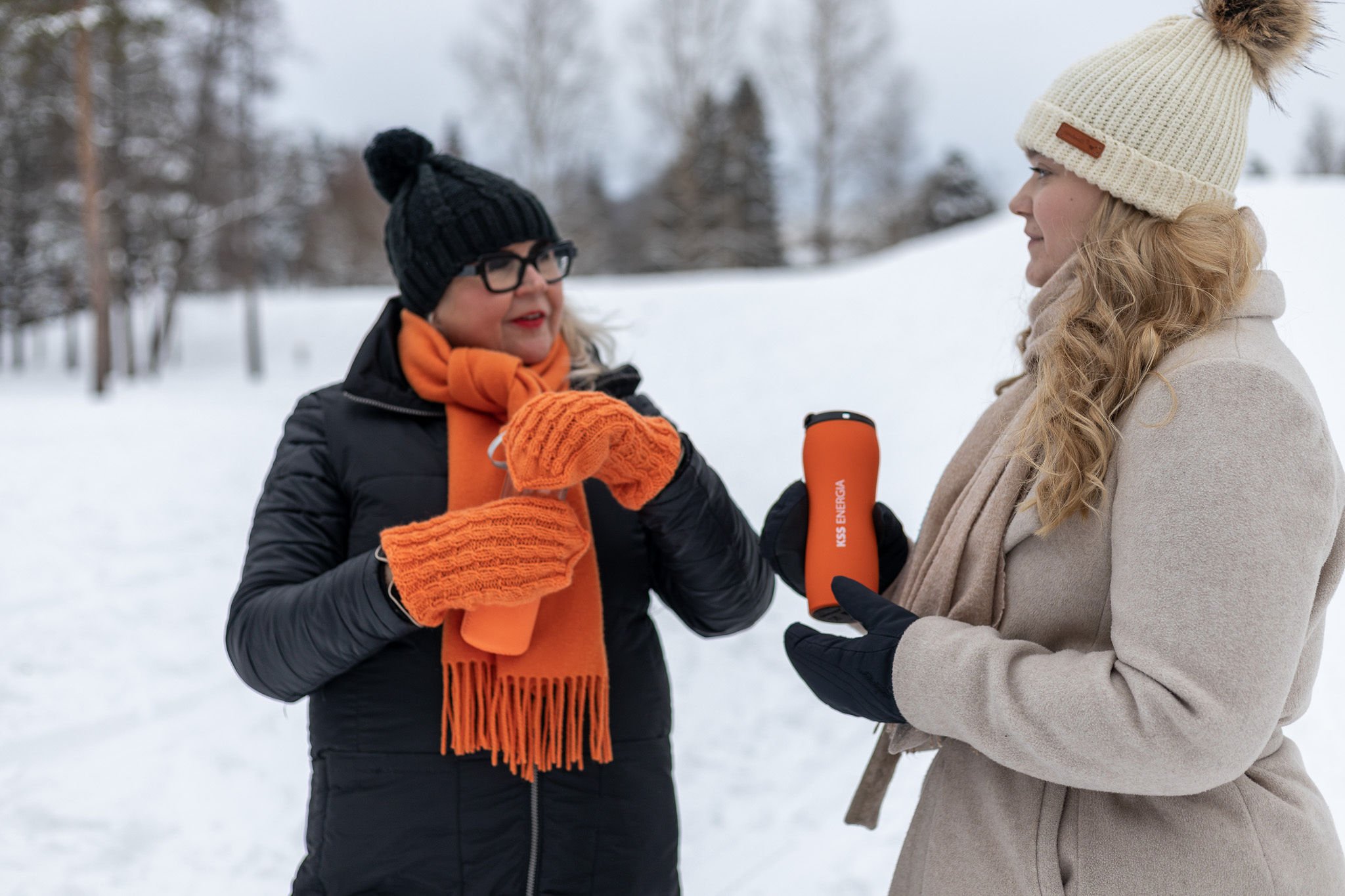 Kaksi hymyilevää naista ulkona talvella. 