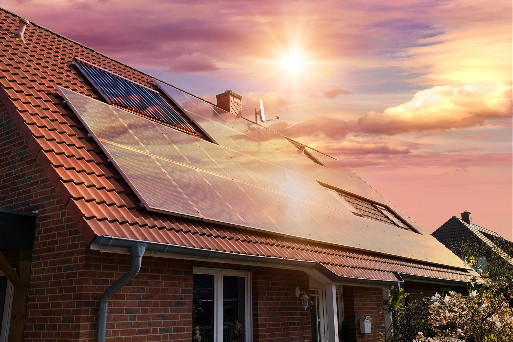 Ilta-aurinko heijastuu talon katolla olevista aurinkopaneeleista.