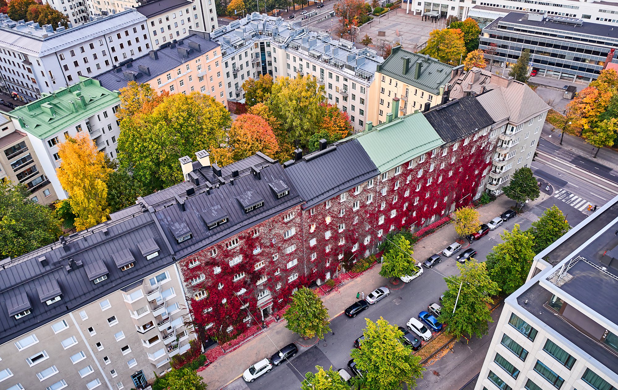 Ilmakuva Helsingin kaupungista, jossa näkyy eri värisiä kerrostaloja ja autoja sekä katuja.